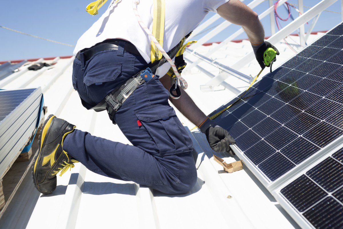 Worker installing solar panels on roof.